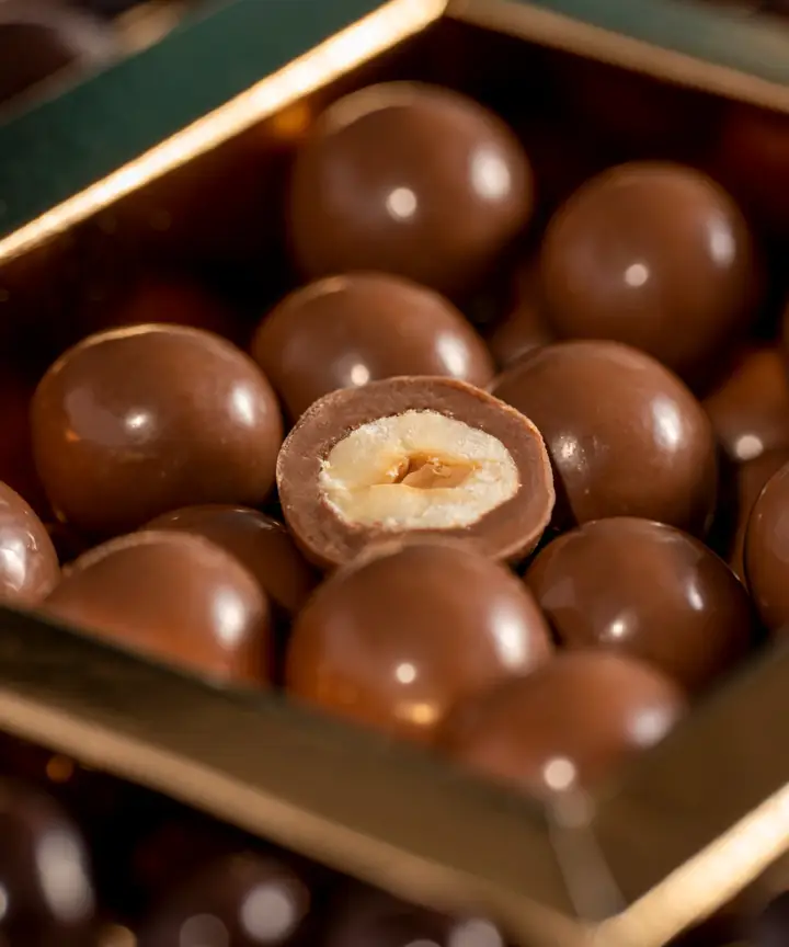 Dragées: nocciole ricoperte di cioccolato al latte in una scatola, una spezzata a metà