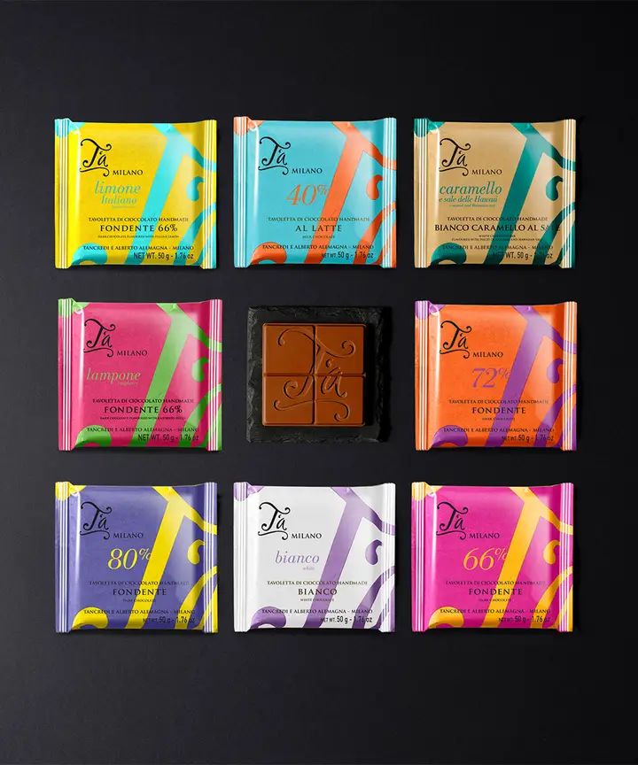 Nove tavolette di cioccolato T'a nelle loro carte colorate, gialla, azzurra, rosa, arancio e viola, su fondo nero